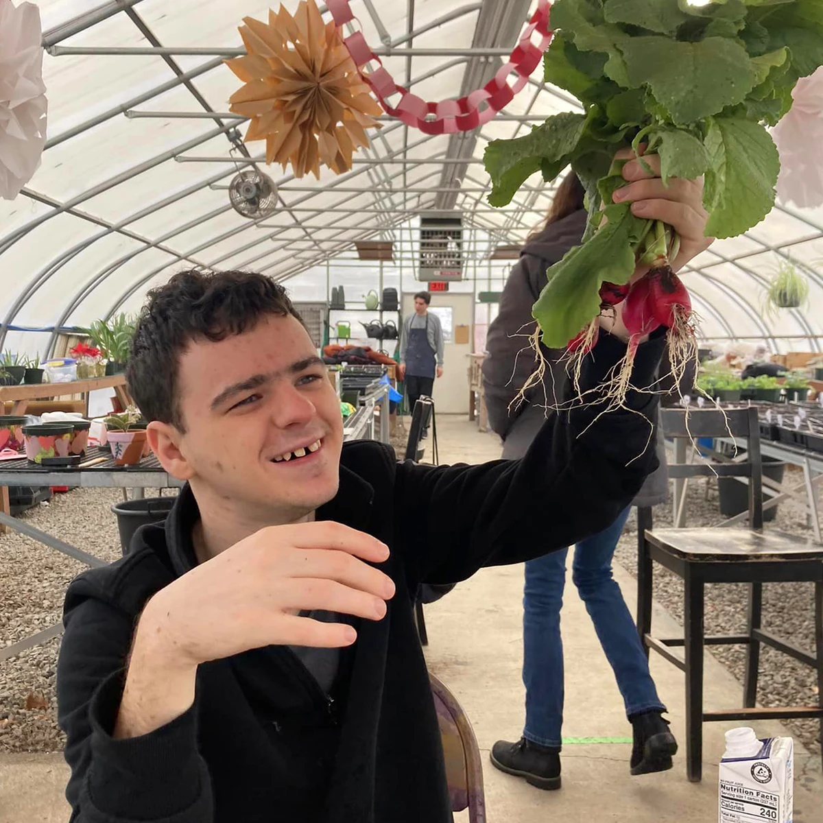 Cushing student admiring growing plant in greenhouse