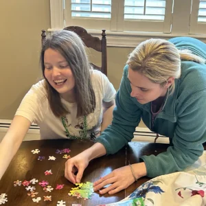 Cushing adult and staff working on a puzzle together