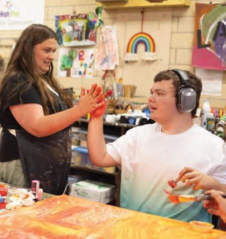 Art teacher Emily McElman high fives student Mason Austin.