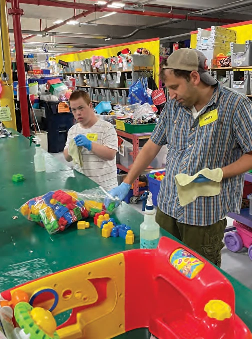 Greg Stevens and Matt Dane sanitizing colorful toy blocks at Gifts to Give