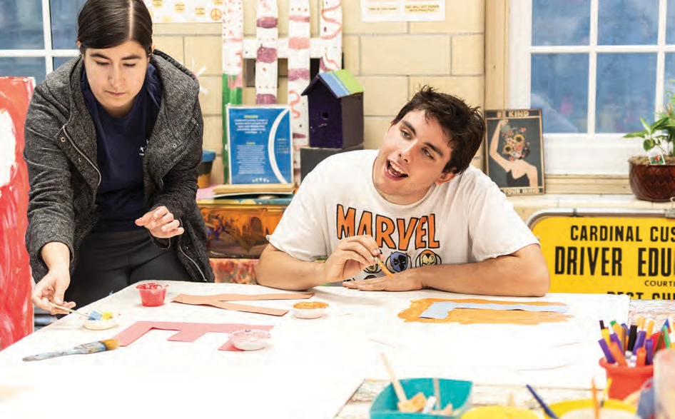 Student Griffin Browne working with staff member Elizabeth Abbott to create a panel with the word “love”