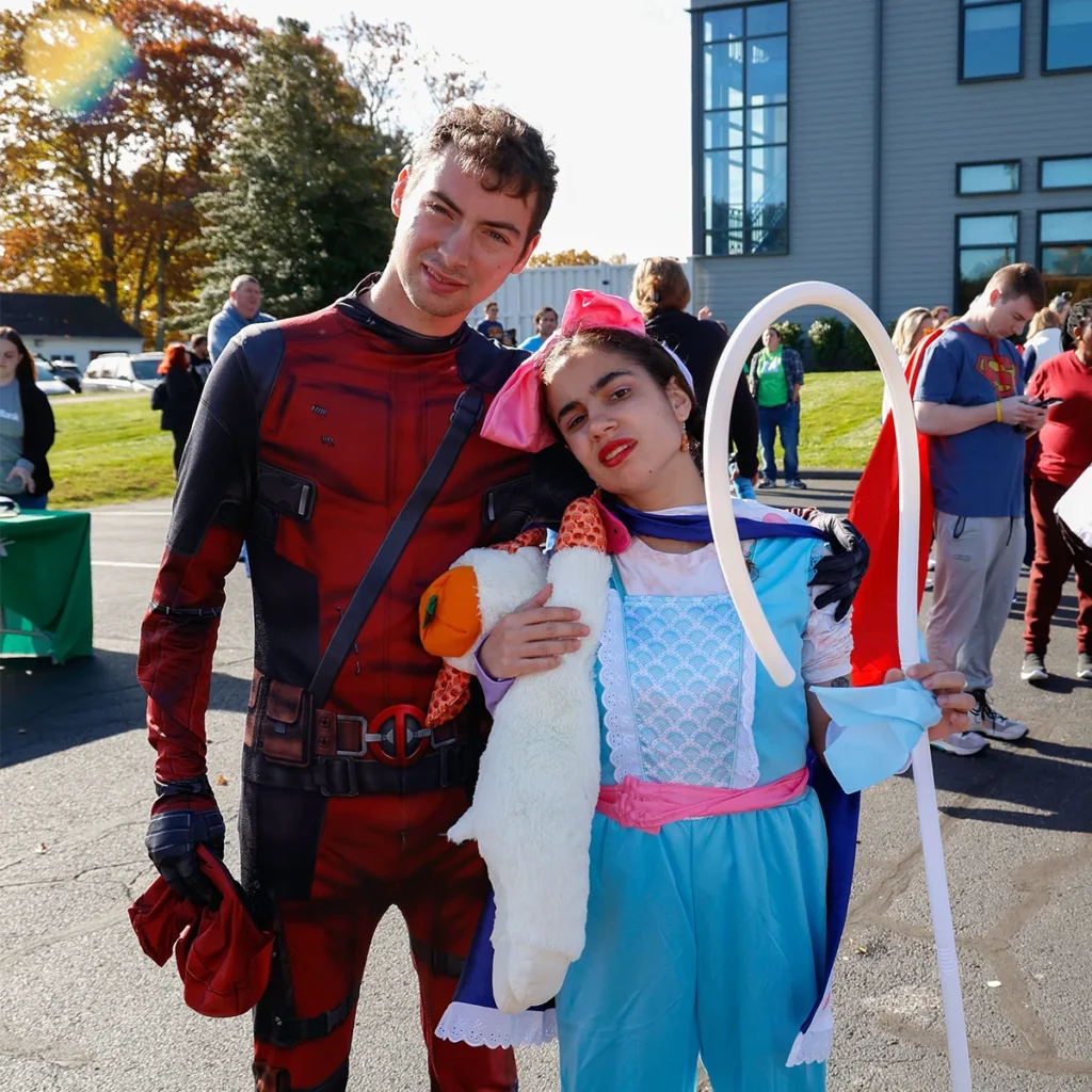 Two Cardinal Cushing students dressed in costume. One is dressed as Deadpool and the other as Little Bo Peep with a stuffed animal sheep.