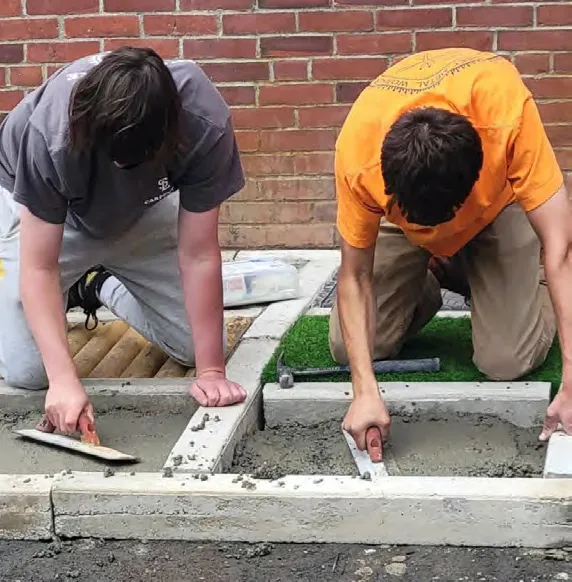 Eagle Scout Joe Hamblin (orange shirt) and his troop build a sensory path for the Cushing community.
