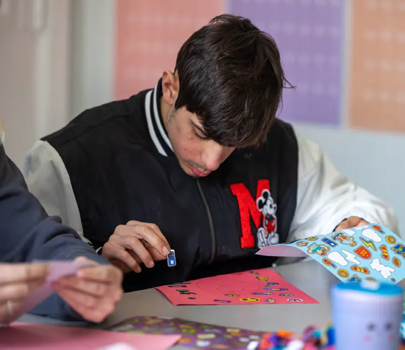 Student Dylan Singer places stickers on a collage.