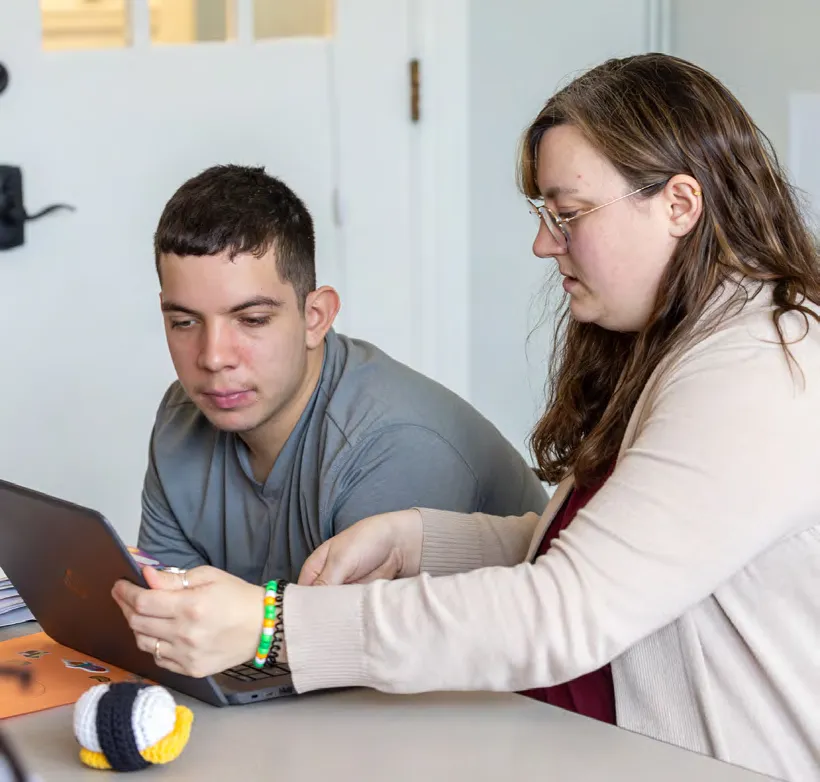 Hannah Meallo works on a laptop with student Xavier Morales.